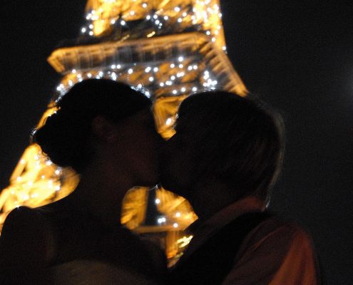 Couple de maries s'embrassant avec la Tour Eiffel illumine de nuit