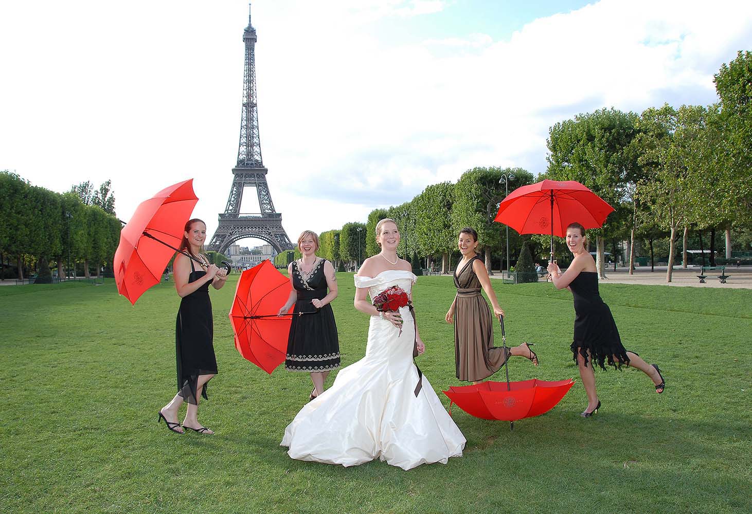 Wedding with bride, guests and red umbrellas, Eiffel Tower gardens, Paris, France